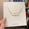 Detailansicht eines eleganten goldenen Wellenarmbands mit funkelnden Strasssteinen auf Karte - Gold