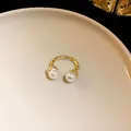 Close-up detail of a vintage style wrinkled gold open ring featuring elegant dual white pearls - Gold