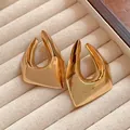 Macro detail of irregular chunky geometric gold plated earrings on cream velvet jewelry tray - Gold