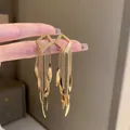 Close-up of golden geometric earrings with long chain tassels and leaf-shaped drops - 25# Gold Rhombus Tassel (25#)