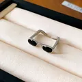 Detailed macro shot of a minimalist silver eyeglasses-shaped open ring with black oil finish. - Silver-Black