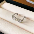 Detailed macro shot of a creative silver glasses-shaped open ring in a display box - Silver-Transparent