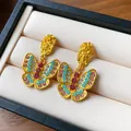 Detailed macro shot of vintage gold butterfly drop earrings with colorful rhinestones - Pleated Butterfly Style (WE196) / Gold