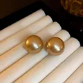 Primo piano di eleganti orecchini a lobo con perle color champagne in un cofanetto bianco - Oro