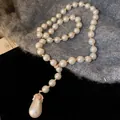 Dettaglio ravvicinato di un'elegante collana di perle a goccia con strass lucidi - Catena da maglione / Collana-Bianco