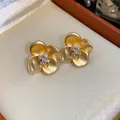 Detailed view of matte gold flower stud earrings with sparkling pave zircon in jewelry box - Gold