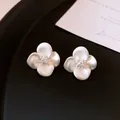 Elegant white satin flower stud earrings with sparkling zircon center on black tray - White