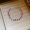 Detailed view of a silver-tone bracelet with sparkling round red zircon stones - Round Style / Red