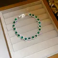 Detailed view of sparkling emerald green cubic zirconia bracelet in a velvet gift box - Round Style / Green