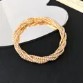 Detailed view of a luxury gold multi-layer rhinestone coiled bracelet on black background - Gold