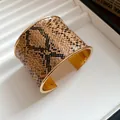 Close-up of a wide cuff bracelet featuring a brown snakeskin pattern and gold interior - Wide Band Open Style / Gold Brown Snake Print