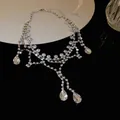 Vue détaillée d'un collier élégant en strass argenté avec gouttes d'eau sur noir - Style Gland Géométrique Goutte d'Eau en Strass / Argent