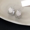 Primer plano de pendientes de plata en forma de C con una textura arrugada única y elegante - Estilo Arrugado Geométrico en C / Plateado