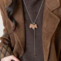 Detalle de un collar de poni flocado con cuenta de ojo de tigre sobre un jersey marrón - 54# Collar-Dorado-Caballo marrón flocado