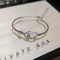 Close-up of silver-tone bracelet with sparkling zircon-studded heart and infinity design - Hollow Heart Style / Silver