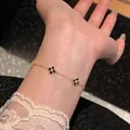 Close-up of a gold plated adjustable bracelet with black zirconia flower charms on a wrist. - Gold-Black
