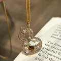 Close-up detail of a luxury gold hollow gourd necklace featuring white pearls and tiger eye stone - Hollow Gourd Necklace / Gold