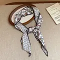 Detail view of vintage paisley print silk scarf necklace on rustic linen background. - Black-White