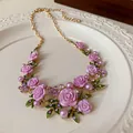 Vista dettagliata di rose in resina rosa e perle su una collana floreale dorata. - Collana / Viola