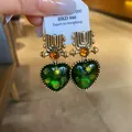 Close-up of vintage gold-tone heart earrings with vibrant green resin and amber accents. - Silver Earring Post Style / Green