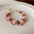 Vista dettagliata di una collana pastorale con rose rosa, perle e strass luccicanti - Bracciale / Rosa