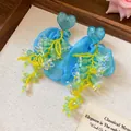 Dettaglio di orecchini a fiore in chiffon blu con borchie a cuore e nappe di perline. - Stile Nappa Cuore Perno Argento / Blu Giallo e Verde