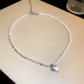 Elegant close-up detail of a silver heart pendant on a pearl and metal chain necklace - Silver (Heart)