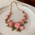 Dettaglio macro di una collana con rose rosa in stile pastorale con strass e perle - Collana / Rosa
