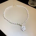 Close-up view of a French chic pearl necklace with a white camellia flower pendant - Gold (Camellia)