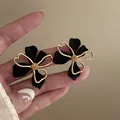 Close-up detail of French vintage black matte flower stud earrings with gold trim - Silver Post (HE21750) / Black