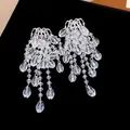 Close-up of sparkling water-drop crystal tassel earrings on elegant black velvet. - Glass Style / Silver
