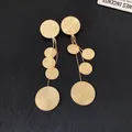 Detailed view of textured golden circular tassel earrings with elegant silver needle posts - Gold