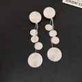Detailed macro view of silver round dangle earrings with spiral texture and long tassels - Silver