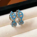 Detailed macro view of silver hoop earrings with blue stones in Chaine d'Ancre design. - Pig Nose Huggie / Silver-Blue