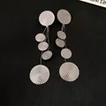 Close-up detail of silver-toned dangle earrings featuring multiple textured circular discs - Black