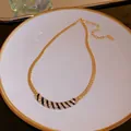 Macro detail of a gold plated curved necklace featuring black and white rhinestone stripes - Curved Clavicle Chain Style 2