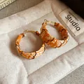 Detailed close-up showing the orange paisley fabric texture on bohemian hoop earrings - Brown