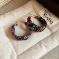 Close-up of bohemian fabric printed hoop earrings with red wave stitching detail - Green