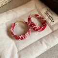 Close-up of red paisley print fabric hoop earrings with gold-tone hardware - Red