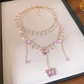 Detailansicht einer eleganten mehrlagigen Goldkette mit funkelnden lila Strass-Schmetterlingen - Schmetterling Blume Quaste Mehrlagiger Stil / Gold Lila