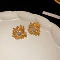 Macro detail of golden daisy earrings with sparkling central crystals on a cream plate - 3D Floral Rhinestone Earrings (14#)