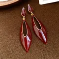 Detailed macro shot of vintage red enamel teardrop hollow earrings with gold trim - Red