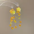 Close-up of yellow floral earrings with tiered faceted bead tassels and silver studs. - Style 31 Silver Post