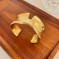 Close-up detail of chunky gold liquid irregular wavy cuff bracelet with metallic sheen - Gold