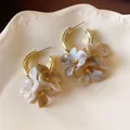 Close-up of French retro hoop earrings with marbled acrylic flower dangles - Silver Post-Tie-Dye Flower / Gold-Light Coffee