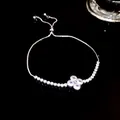 Detailed view of a silver adjustable bracelet with a sparkling clover charm on black. - Single Flower Slider Style (5273621715168) / Silver