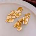Elegante mattgoldene Blumenohrringe im französischen Stil auf einem cremefarbenen Teller - 22# Gold Silberstecker