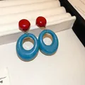 Detailed macro shot of stylish red and blue geometric oval hoop earrings on a display tray - Contrast Geometric (24)