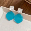 Close-up detail of geometric irregular blue and white resin drop earrings on a tray - Geometric Irregular Style (30)