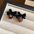 Dettaglio macro di orecchini a fiocco floccato nero con perle ambrate vintage - Fiocco / Nero